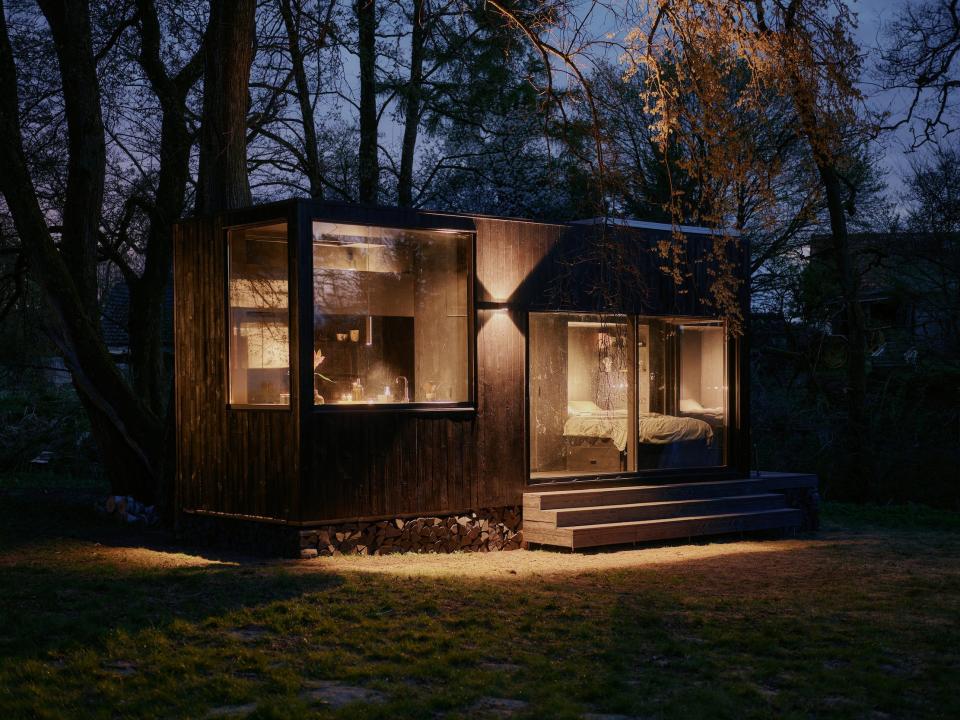 A Raus cabin glowing with the lights on at night