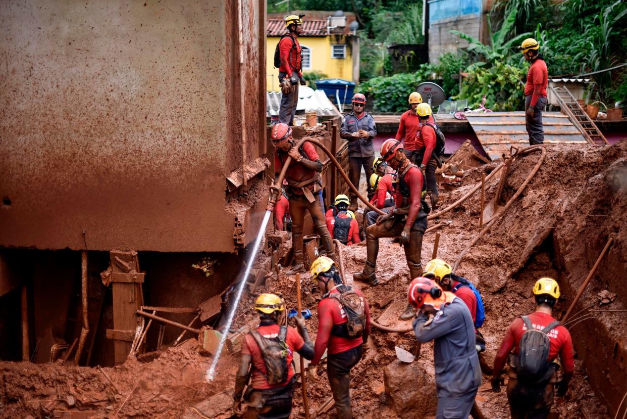 Firefighters search for missing persons using a hydraulic dismantling technique, which uses water to disperse mud, in Vila Bernadete: AFP via Getty Images