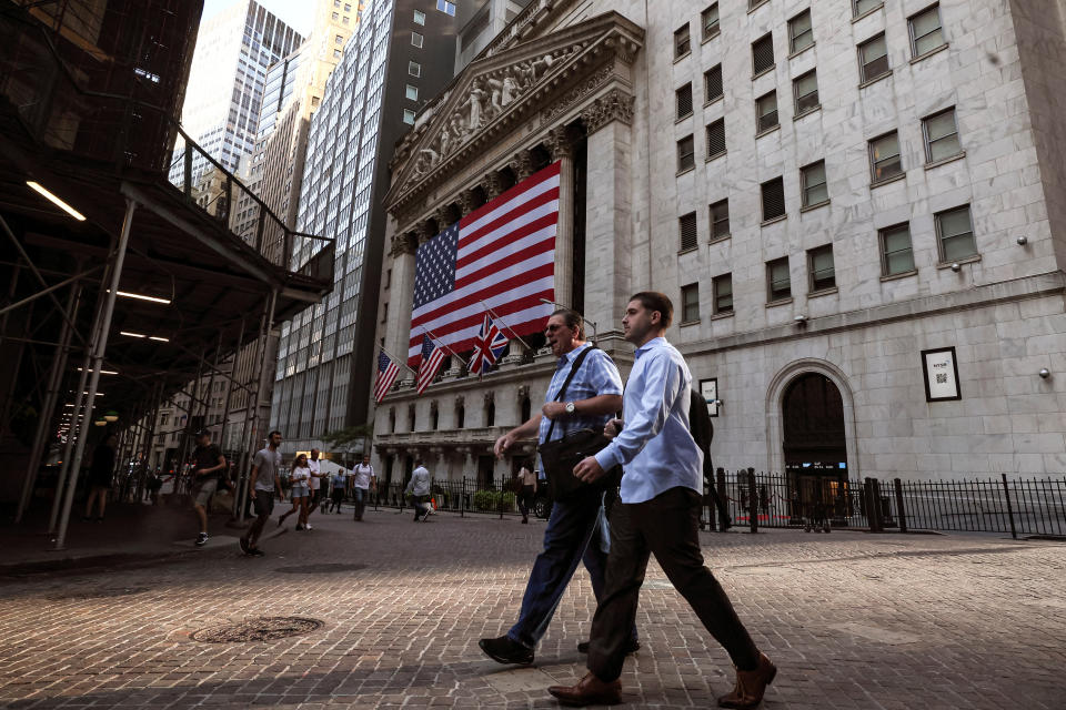 Morning commuters walk on Wall St. as the Union Jack flies at half staff outside the New York Stock Exchange (NYSE) in New York City, U.S., September 9, 2022.  REUTERS/Brendan McDermid