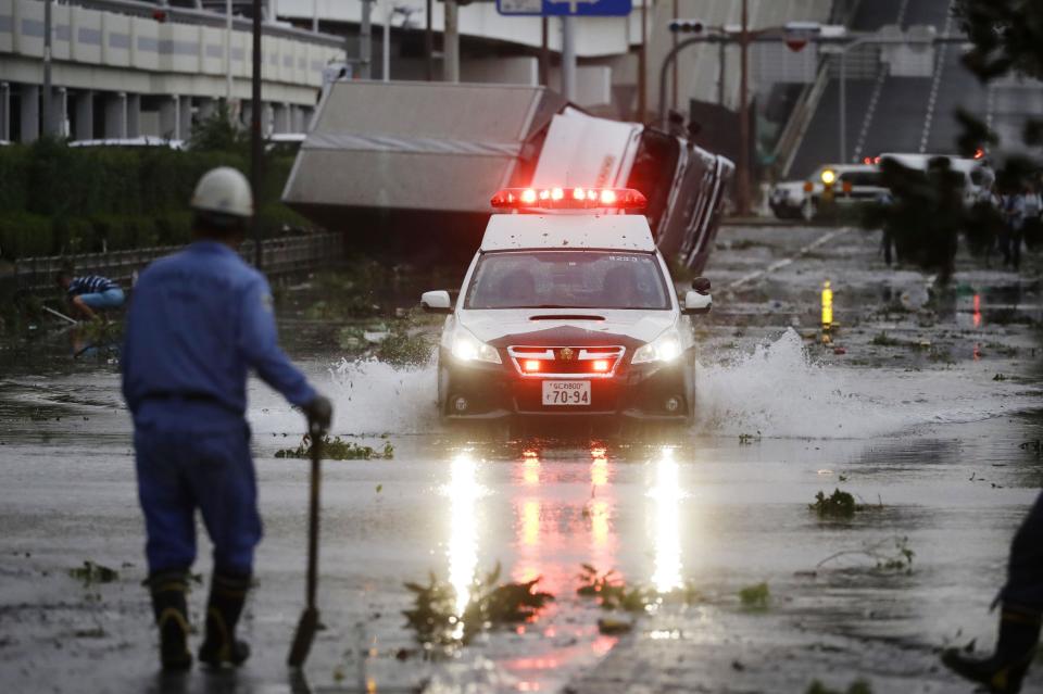 A police car makes through a flooded road following a powerful typhoon in Osaka, western Japan, Tuesday, Sept. 4, 2018. A powerful typhoon blew through western Japan on Tuesday, causing heavy rain to flood the region's main offshore international airport and high winds to blow a tanker into a connecting bridge, disrupting land and air travel. (Kota Endo/Kyodo News via AP)