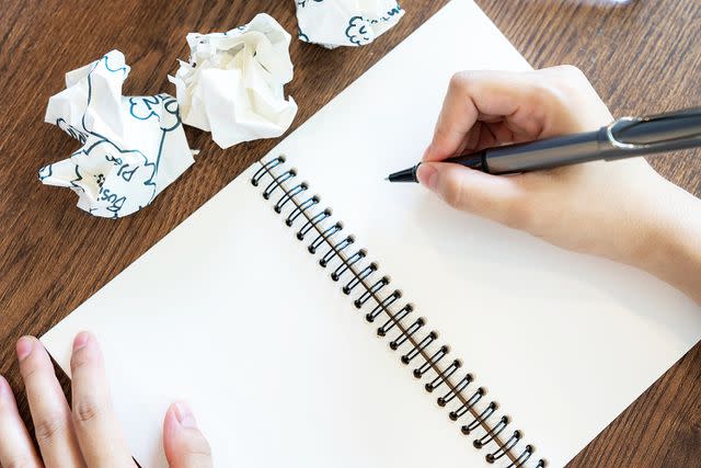 <p>Virojt Changyencham/Getty</p> A stock image of a person writing on paper