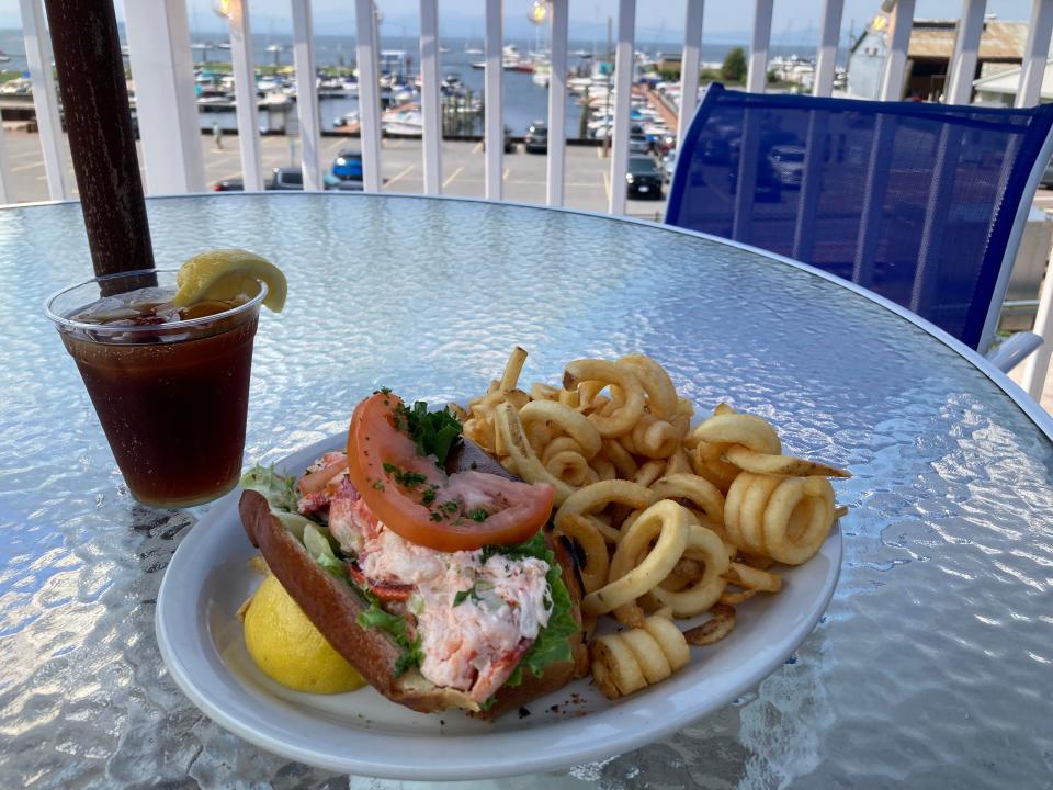 A lobster roll, curly fries and an iced tea on the deck of Shanty on the Shore in Burlington on July 26, 2023.