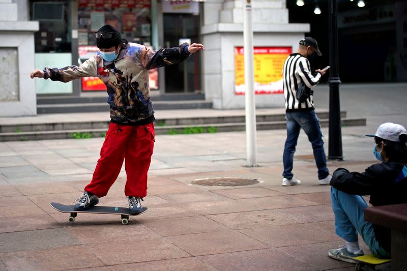 Un hombre con una marcarilla patinando en una calle de Wuhan