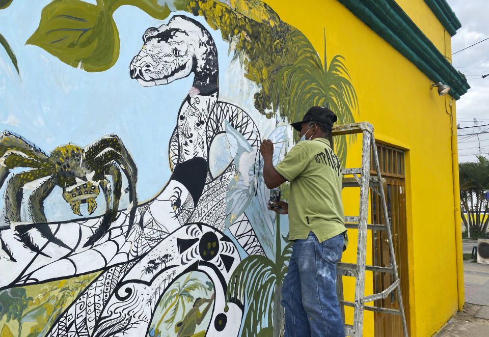 A painter draws a snake in the commercial area of Leticia, in Colombia's Amazon on June 15, 2022. Gustavo Petro, Colombia's first elected leftist president, will take office in August with ambitious proposals to halt the record-high rates of deforestation in the Amazon. (AP Photo/Fabiano Maisonnave)