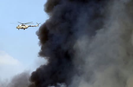 A military helicopter flies over clouds of smoke and as it tries to extinguish a fire at Cairo International Convention Centre (CICC) in Cairo's Nasr City district March 4, 2015. REUTERS/Amr Abdallah Dalsh