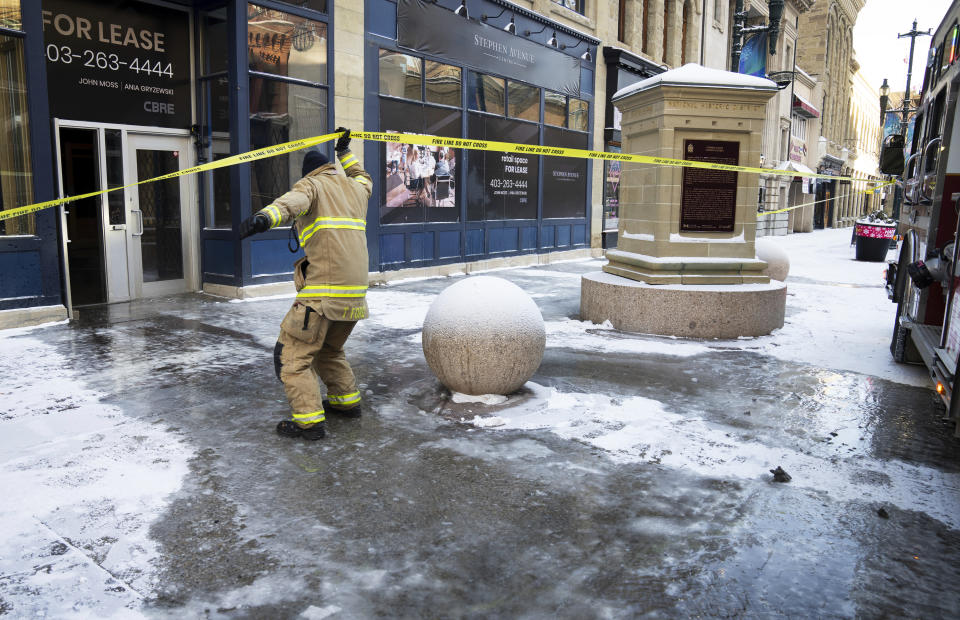 A firefighter slips on frozen water from a water line break as freezing temperatures as low as -38 celsius have hit the city of Calgary, Alberta, Monday, Jan. 15, 2024. (Todd Korol/The Canadian Press via AP)