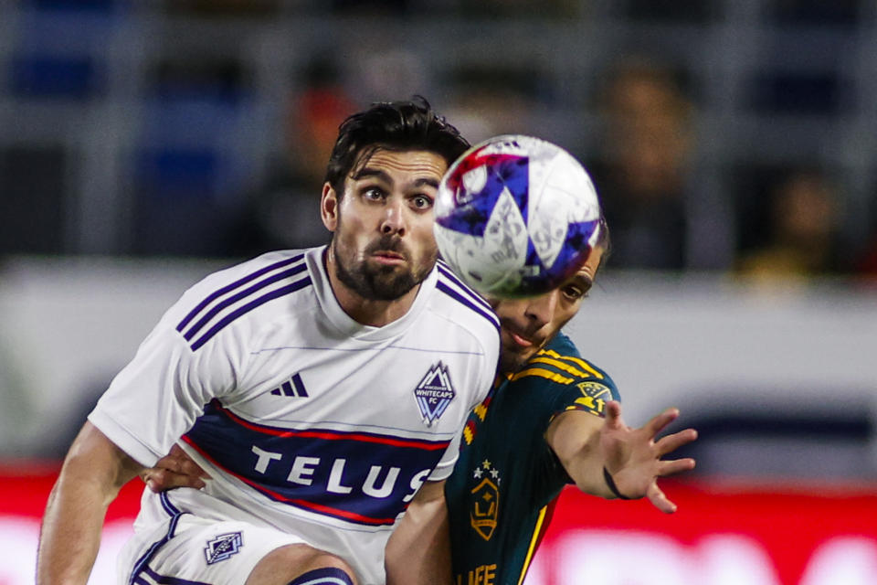 Vancouver Whitecaps forward Brian White, left, and LA Galaxy defender Martín Caceres vie for the ball during the second half of an MLS soccer match in Carson, Calif., Saturday, March 18, 2023. (AP Photo/Ringo H.W. Chiu)