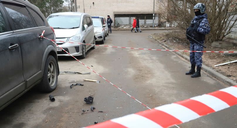 A police officer guards an area with the wreckage of a drone near a damaged apartment's building after a reported drone attack in St. Petersburg, Russia, Saturday, 2/03/24.