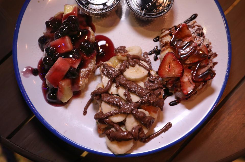 The Crowaffles Platter, featuring one each of croissant waffles topped with blueberry compote and pineapple, left, banana and Nutella, center, and strawberries and chocolate sauce, right, served from the Breakfast & Brunch Menu at the newly opened OFC's The Old Farm Cafe & Dining Experience in Winton Place in Brighton.