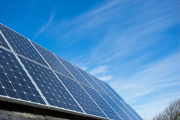 Solar panels on a roof with a sunny sky in the background.