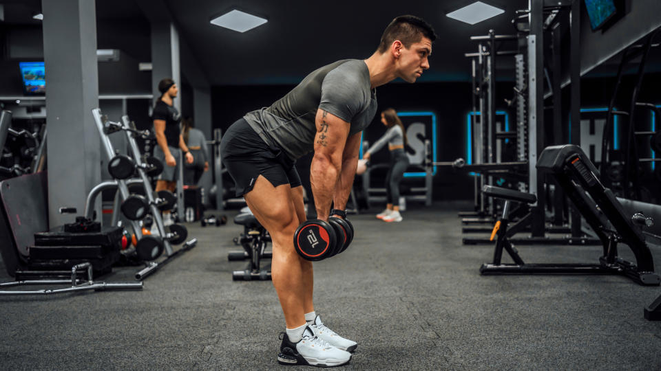 A man performing a dumbbell Romanian deadlift