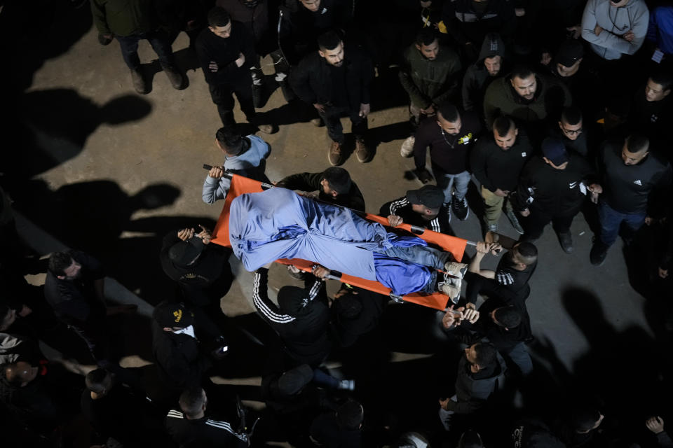 Palestinians carry the body of a man who was killed during an Israeli military raid in the West Bank city of Jenin, Tuesday, March 7, 2023. The raid led to a gunbattle that killed at least six Palestinians. Israeli officials said the target was a militant who killed two Israeli brothers in a West Bank shooting last week. The man was among those killed on Tuesday. (AP Photo/Majdi Mohammed)