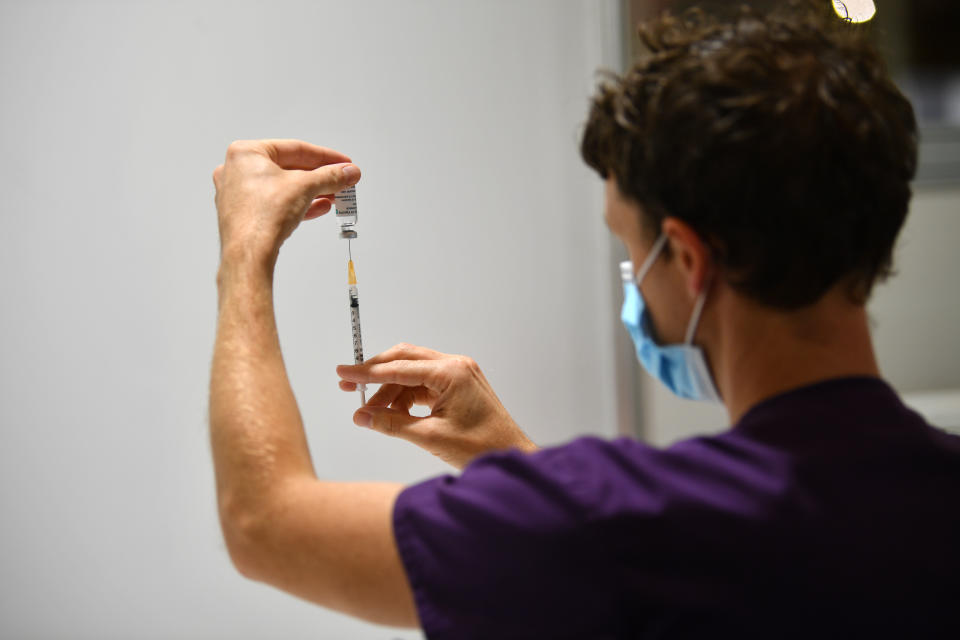 A healthcare worker is seen handling a AstraZeneca vaccination.