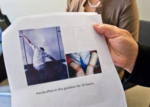 Falun Gong practitioner, Ma Chunmei, holds a photo showing a prisoner handcuffed between two beds and the marks left by handcuffs, as she and Wang Chunying are interviewed at the AFP offices in Washington, DC, on April 30, 2013