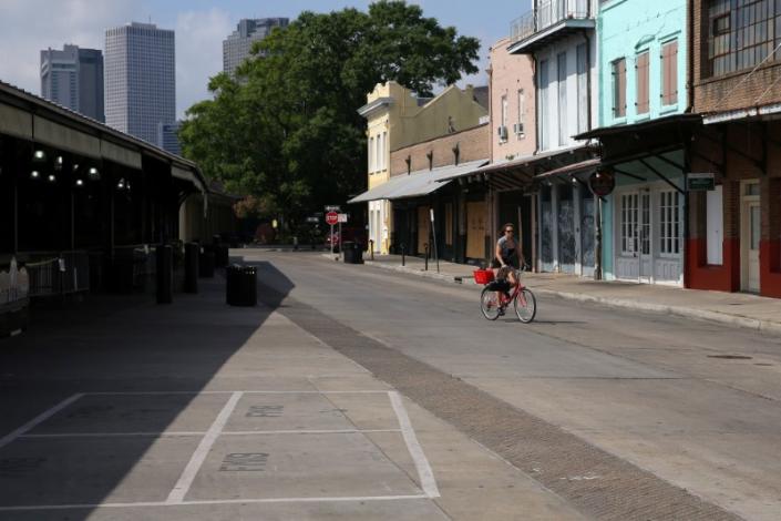 A woman rides her bike through the empty French Market in the French Quarter neighborhood, following the outbreak of the coronavirus disease (COVID-19), in New Orleans