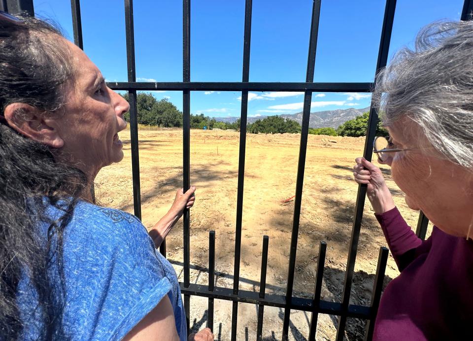 Cousins Denise Martin, left, and Catherine Gutierrez stand at the gate of St. Thomas Aquinas Cemetery outside Ojai, where their grandmother is buried.