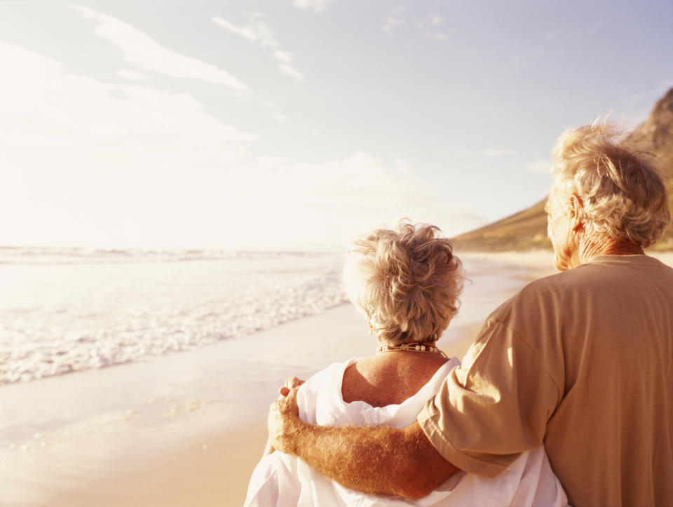 Retired seniors walking on the beach looking at the ocean.