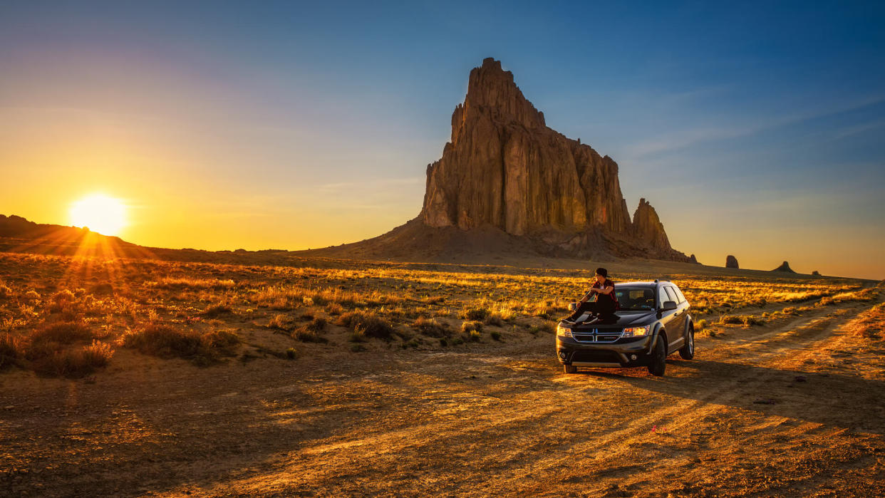 Shiprock, New Mexico, USA - May 14, 2016 : Boy enjoys sunset at Shiprock sitting on the hood of his car.