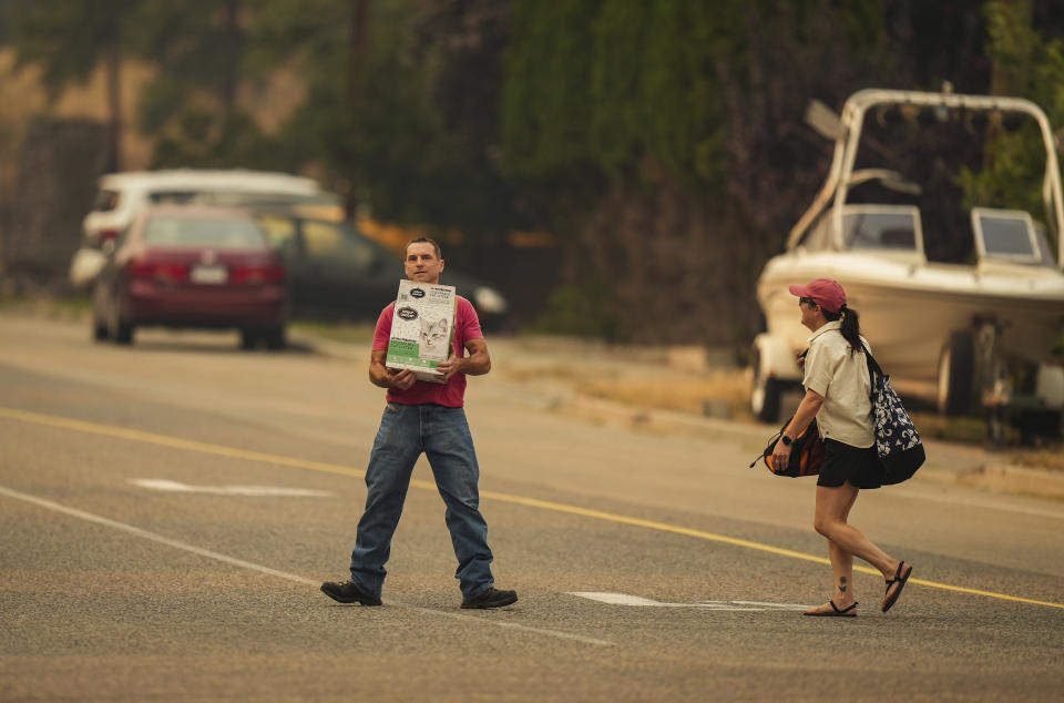 Evacuees leave a neighborhood near Knox Mountain after a wildfire evacuation alert was upgraded to an order in Kelowna, British Columbia, Friday, Aug. 18, 2023. (Darryl Dyck/The Canadian Press via AP)