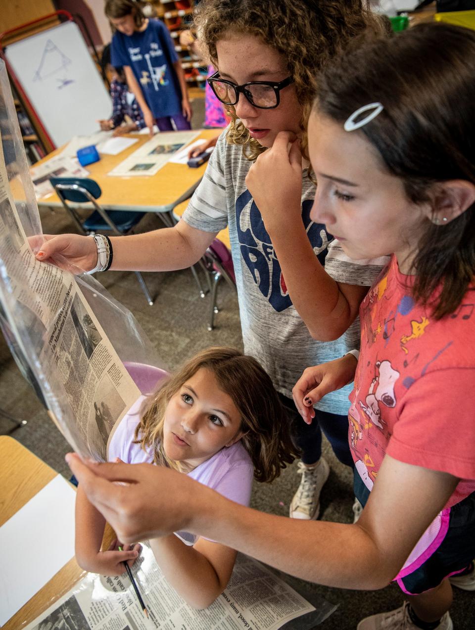 Avonleigh Easton, left, looks up at papers from the Sept. 11, 2001, attacks being held by Alexis Wiesenberg, middle, and Aoife Kaousaleos in Rise Reinier and Kevin Gallagher’s multi-age class at Templeton Elementary on Wednesday, Sept. 11, 2019. Templeton Elementary is one of four MCCSC primary schools that may be consolidated.