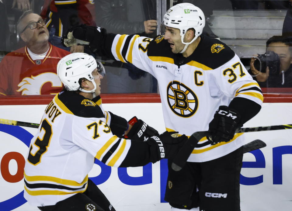 Boston Bruins defenceman Charlie McAvoy, left, celebrates his overtime goal against the Calgary Flames with forward Patrice Bergeron during an NHL hockey game Tuesday, Feb. 28, 2023, in Calgary, Alberta. (Jeff McIntosh/The Canadian Press via AP)