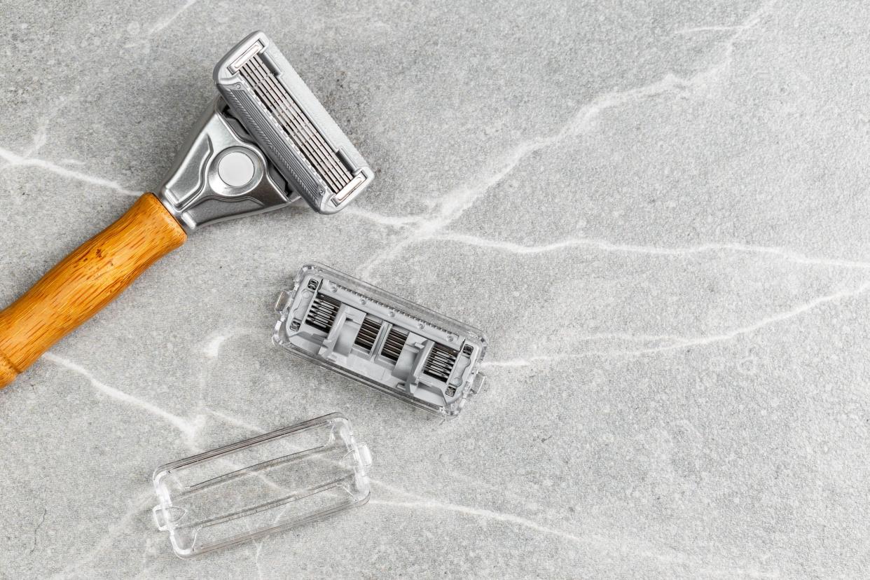 Shaving Razor with wooden handle with refill blade on a grey marble background. Plastic free hygiene tool