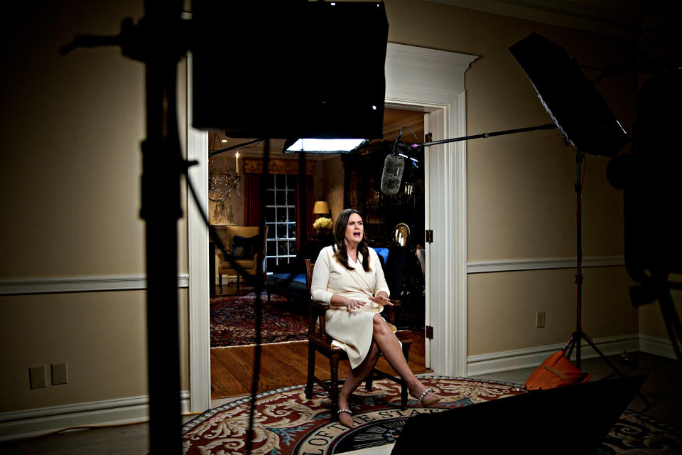 Sarah Huckabee Sanders sits in a doorway under studio lights and before a boom-mounted microphone.