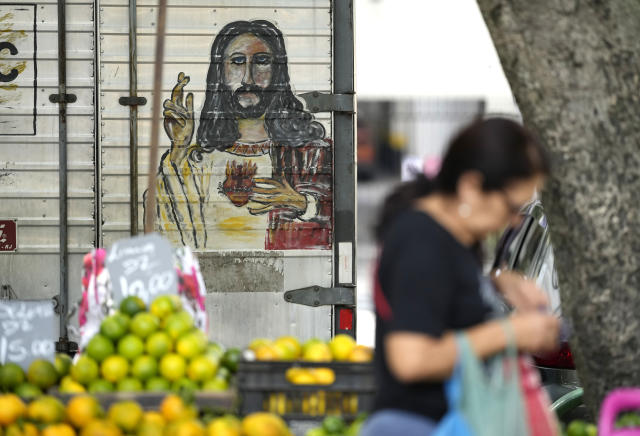 A woman walks past a fruit vendor at a street market in Rio de Janeiro, Brazil, Wednesday, May 11, 2022. High inflation in Brazil is eroding the buying power of consumers and angering potential voters, who fault President Jair Bolsonaro for not doing enough about it. (AP Photo/Silvia Izquierdo)