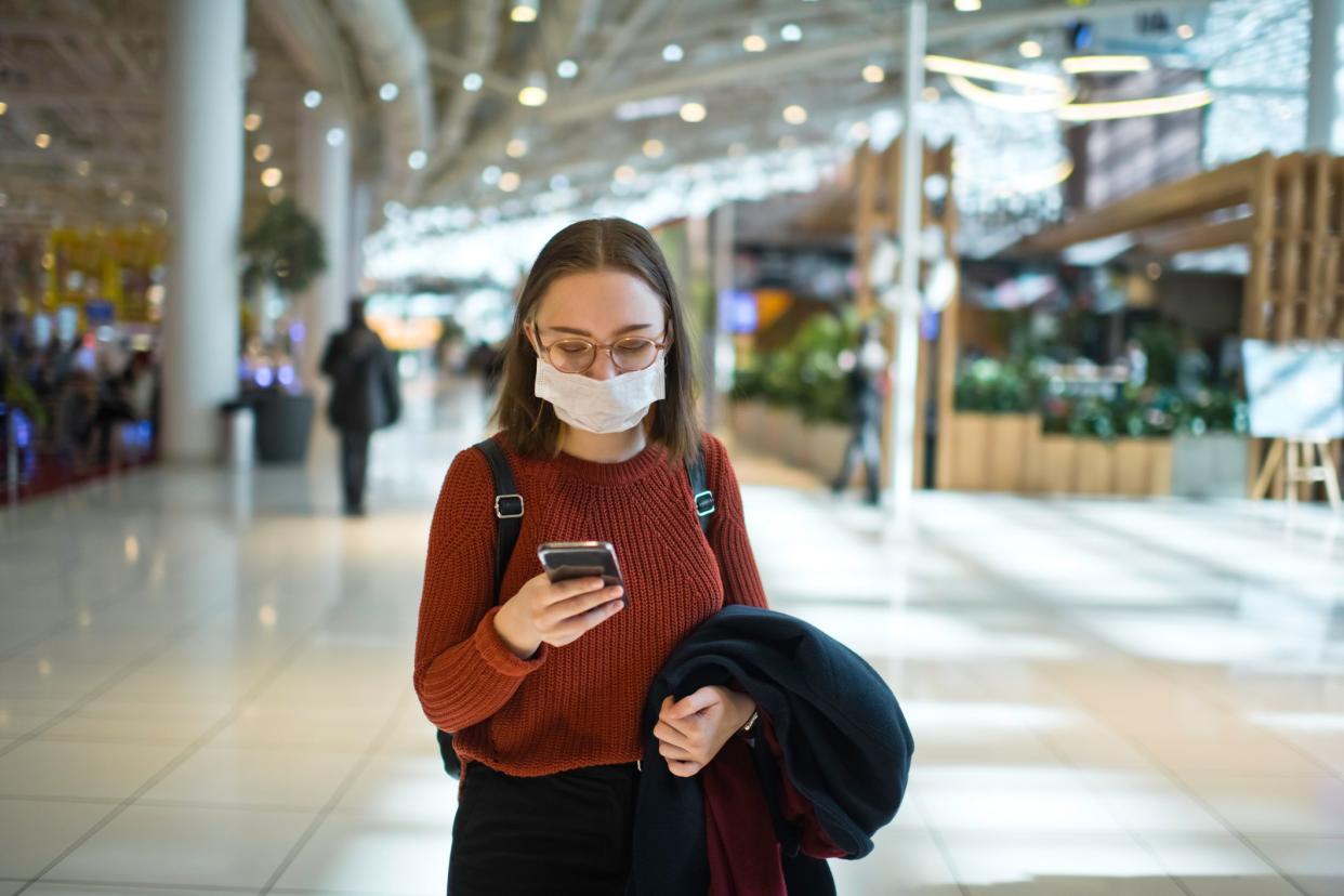 Teenager wearing medical mask protecting herself against virus in a food court of a shopping mall or airport lobby