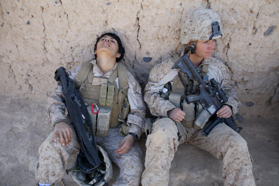 BOLDOC, AFGHANISTAN - NOVEMBER 23: Lance Corporal Luz Lopez, 21, (L) a US Marine with the FET ( Female Engagement Team) 1st Battalion 8th Marines, Regimental Combat team II and Riane Donoho ,21 (R) take a rest during a village medical outreach November 23, 2010 in Boldoc, in Helmand province , Afghanistan. There are 48 women presently working along the volatile front lines of the war in Afghanistan; deployed as the second Female Engagement team participating in a more active role, gaining access where men can't. The women, many who volunteer for the 6.5 month deployment, take a 10 week course at Camp Pendleton in California where they are trained for any possible situation, including learning Afghan customs and basic Pashtun language. (Photo by Paula Bronstein/Getty Images)