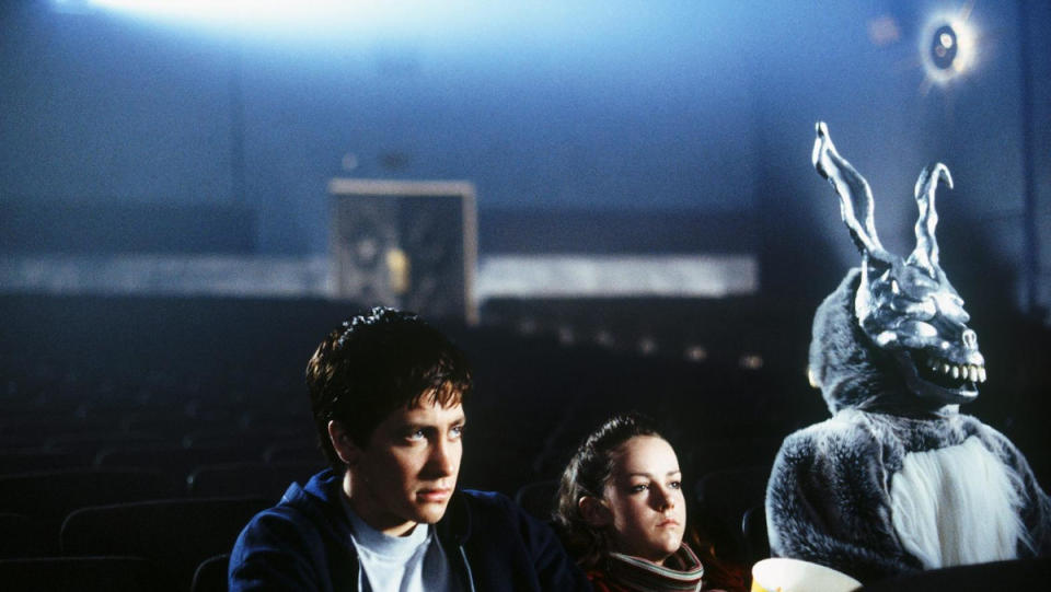 Donnie Darko sits next to his sister and Frank the rabbit in a movie theater