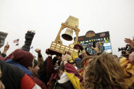 FILE - In this Nov. 9, 2019, file photo,Minnesota fans gather on the field reaching toward the Governor's Victory Bell after Minnesota beat Penn St. 31-26 during an NCAA college football game in Minneapolis. Fans of Minnesota's Golden Gophers are enjoying football success the team hasn't seen in decades, and daring to dream of a trip to Pasadena. (AP Photo/Stacy Bengs,File)