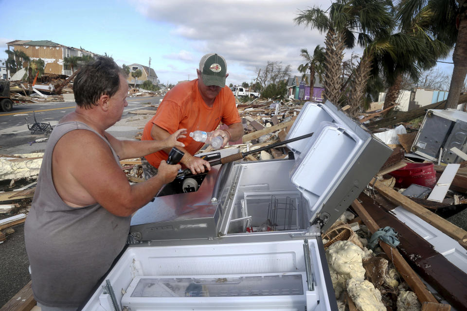 Charles Smith de 57 años, izquierda, y Lee Cathey de 37 años, encuentran botellas de agua en un refrigerador en medio de la US 98 en el pueblo costero de México Beach, Florida. (Douglas R. Clifford/Tampa Bay Times vía AP)