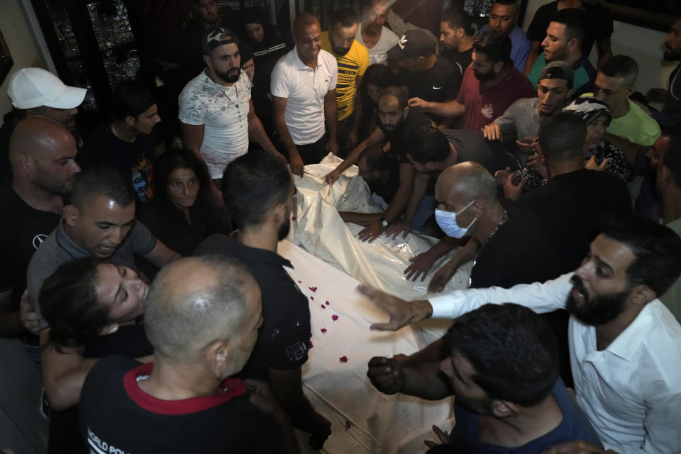 Mourners gather around two of several victims who were on a boat carrying migrants from Lebanon that sank in Syrian waters, after they bring back home their dead bodies, in Tripoli, north Lebanon, Sept. 23, 2022. Syria's health minister says several people have been killed from a boat that sank migrants from Lebanon off Syria's coast. The incident is the deadliest since a surging number of Lebanese, Syrians, and Palestinians have tried to flee crisis-hit Lebanon by sea to Europe. (AP Photo/Bilal Hussein)