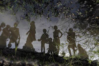 Children standing on a small mud dyke are reflected in the stagnant water, in Langic, Northern Bahr el Ghazal State, South Sudan, Wednesday, Oct. 20, 2021. This is the third straight year of extreme flooding in South Sudan, further imperiling livelihoods in the world's youngest country. A five-year civil war, hunger and corruption have all challenged the nation. Now climate change, which the United Nations has blamed on the flooding, is impossible to ignore.(AP Photo/Adrienne Surprenant)