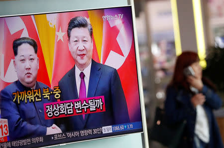 A woman walks past a TV broadcasting a news report on a meeting between North Korean leader Kim Jong Un and Chinese President Xi Jinping in Beijing, in Seoul, South Korea, March 28, 2018. REUTERS/Kim Hong-Ji