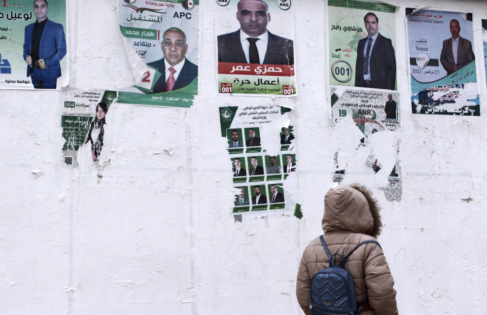 A person walks past promotional posters for candidates in the upcoming municipal election, in Algiers, Algeria, Thursday, Nov. 25, 2021. (AP Photo/ Fateh Guidoum)