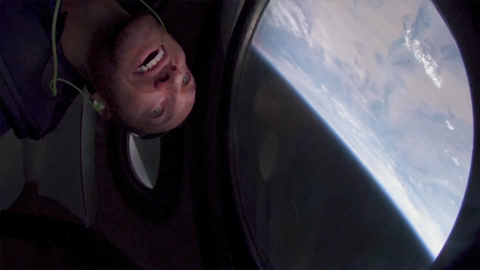 A Virgin Galactic astronaut looks out the window toward earth