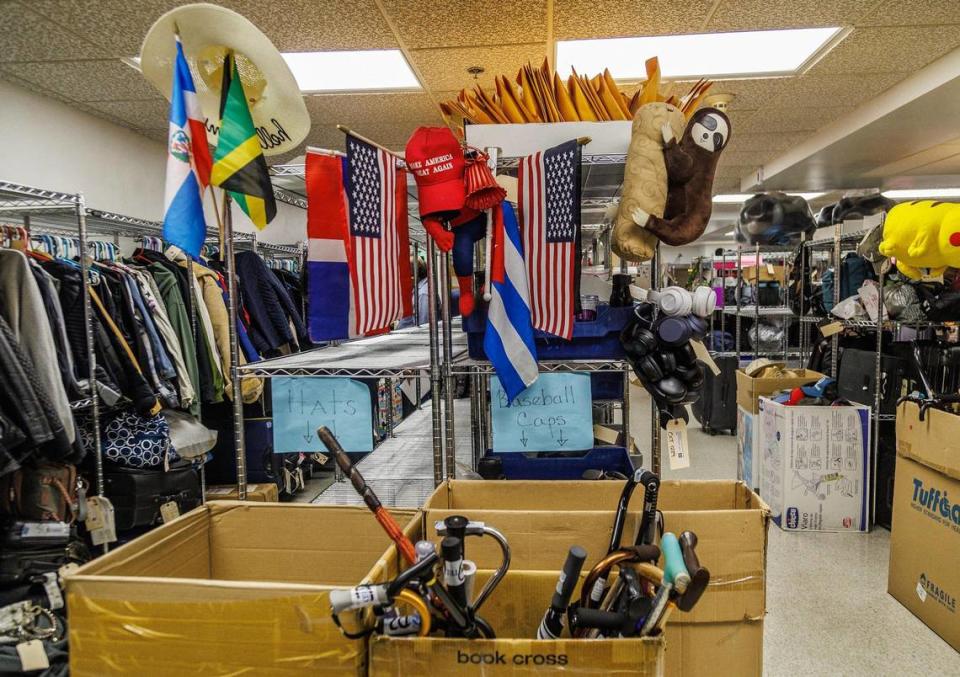 View of a shelf with a variety of items left behind by passengers including flags, walking canes, toys, etc, stored at the Lost and Found department at Miami International Airport, till owners claim them, on Tuesday December 13, 2023.
