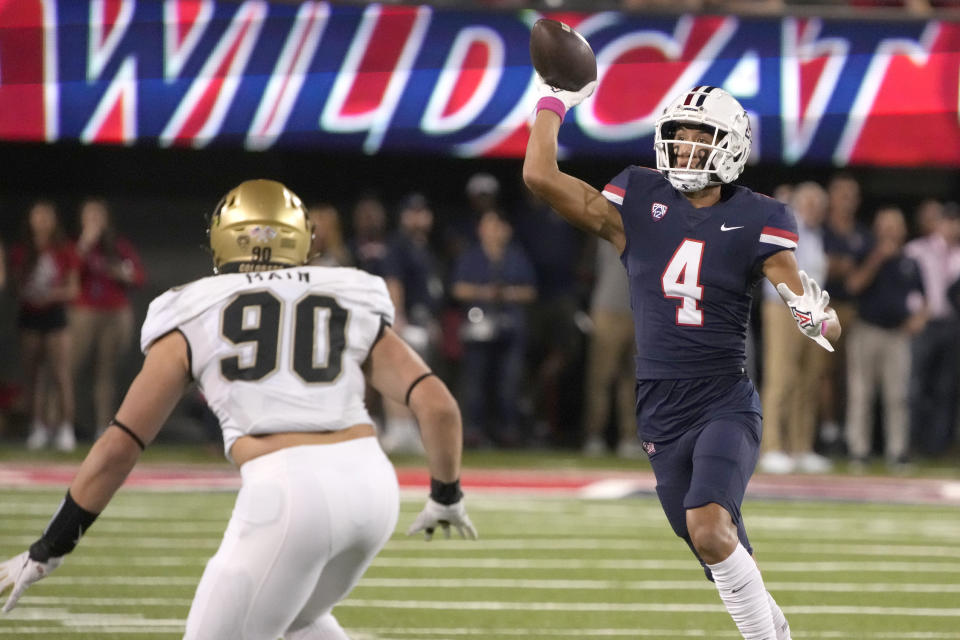 Arizona wide receiver Tetairoa McMillan (4) throws a pass over Colorado defensive end Chance Main (90) during the first half of an NCAA college football game Saturday, Oct. 1, 2022, in Tucson, Ariz. (AP Photo/Rick Scuteri)