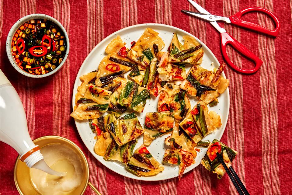 Haemul pajeon sliced into small bites on a white plate sitting on a striped tablecloth.