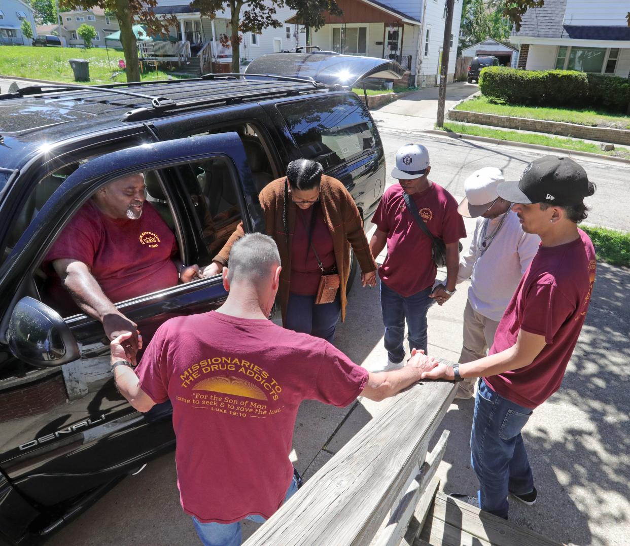 Pastor Kenneth Ivory, left, and members of the Akron Restoration Home gather in prayer before heading out to seek donations on May 17 in Akron.