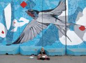 FILE PHOTO: A shoe polishing girl waits for customers under graffiti on a wall in Kabul