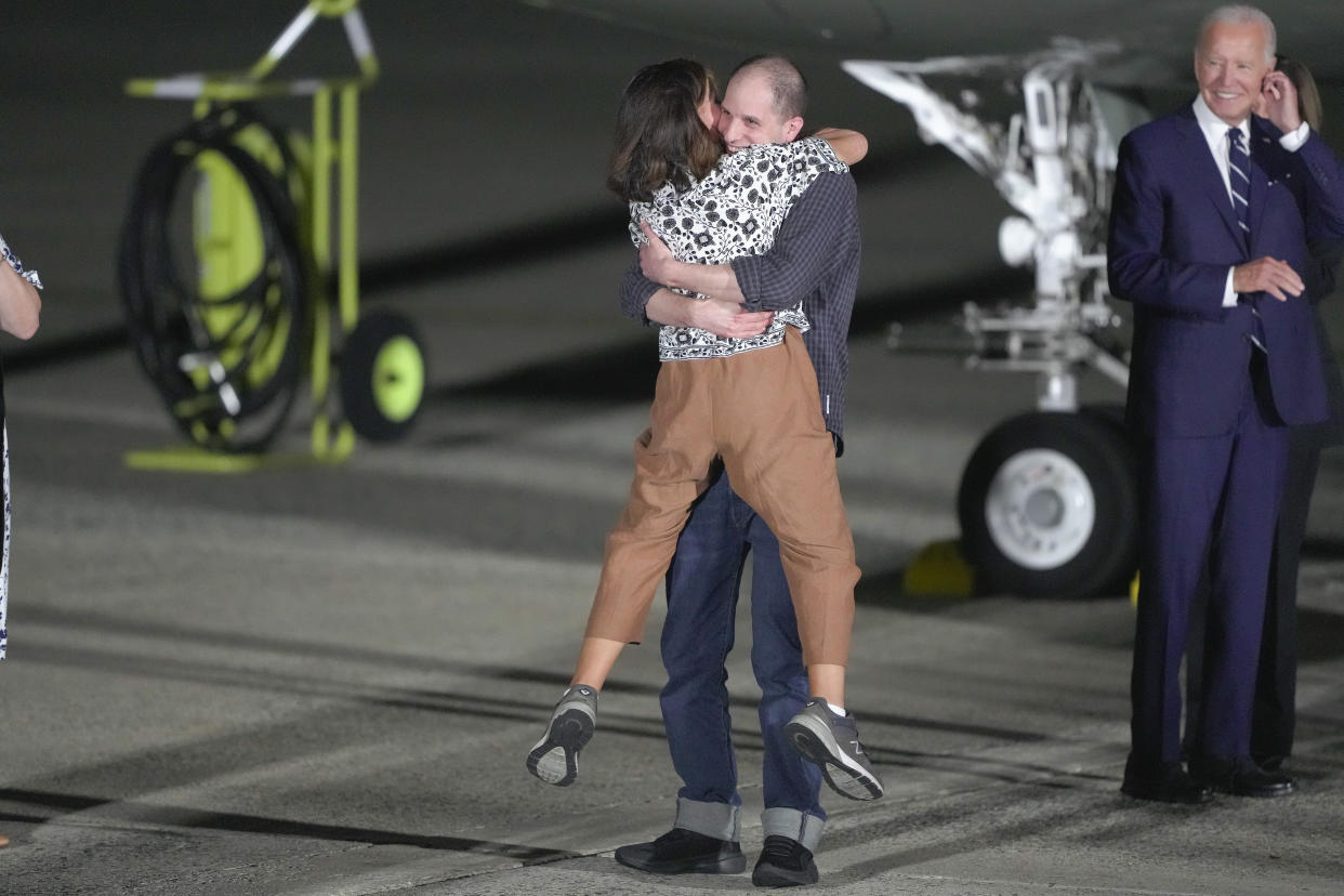 Evan Gershkovich hugs his mother, Ella Milman, as President Biden, right, looks on at Joint Base Andrews on Thursday night. 