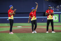 Canadian cricket team captain Saad Bin Zafar waves as he's flanked by teammates Nicholas Kirton, left, and Jeremy Gordon after throwing out the ceremonial first pitch, before the Toronto Blue Jays' baseball game against the Minnesota Twins in Toronto on Friday, May 10, 2024. (Cole Burston/The Canadian Press via AP)