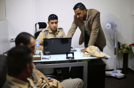 Palestinian Akram Al-Balawi (R), director of Castle Security company, speaks with a private security guard in the company's office in Gaza City November 21, 2016. REUTERS/Ibraheem Abu Mustafa