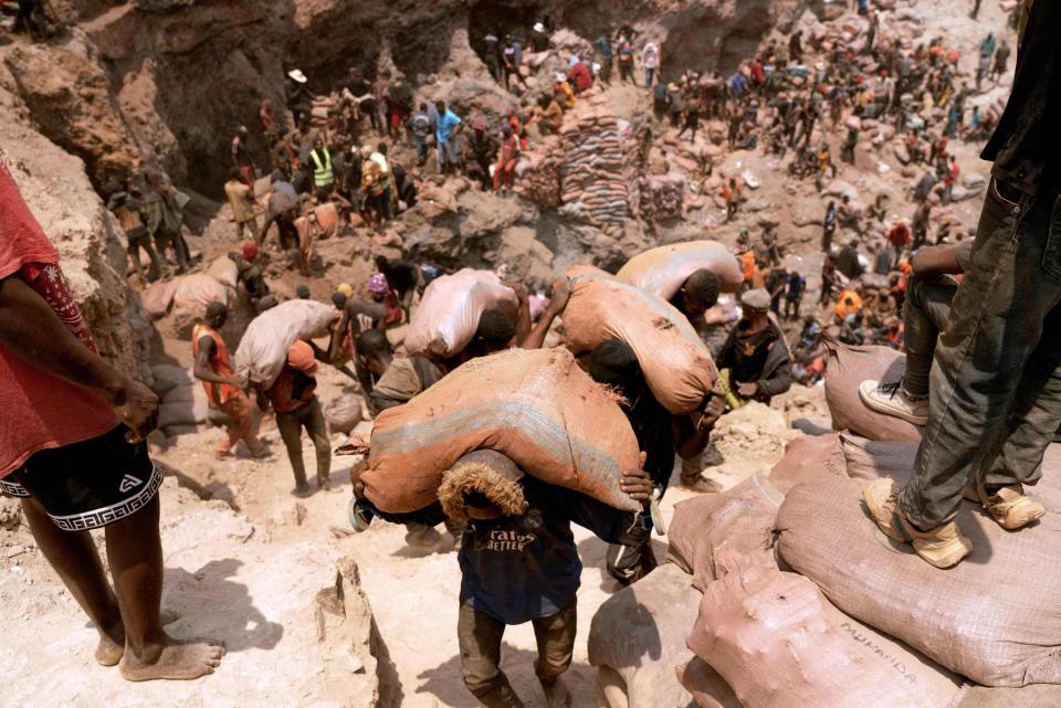 Hundreds of people carrying bags filled with cobalt and covered in orange dust