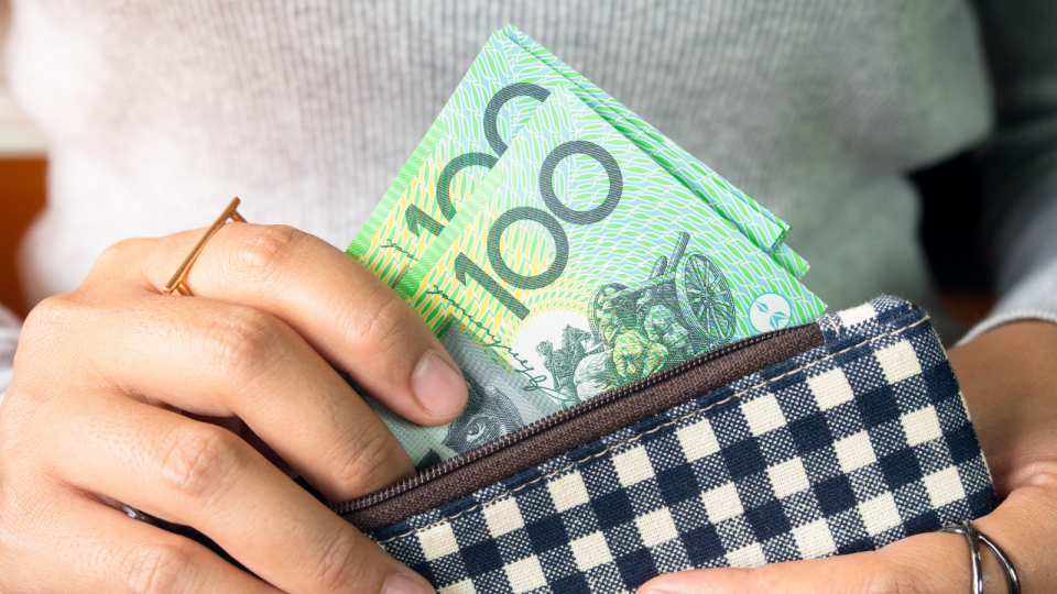 Investing: A person removing $100 notes from a wallet.