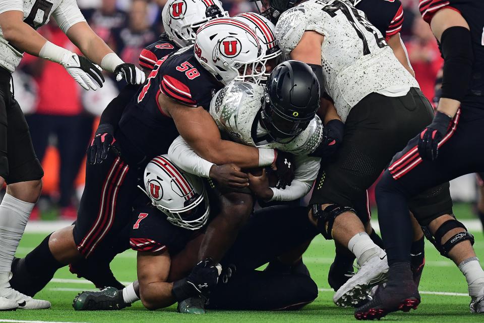 Oregon quarterback Anthony Brown is swarmed under by the Utah defense, led by defensive tackle Junior Tafuna (58) during the first half of Friday's Pac-12 championship game.