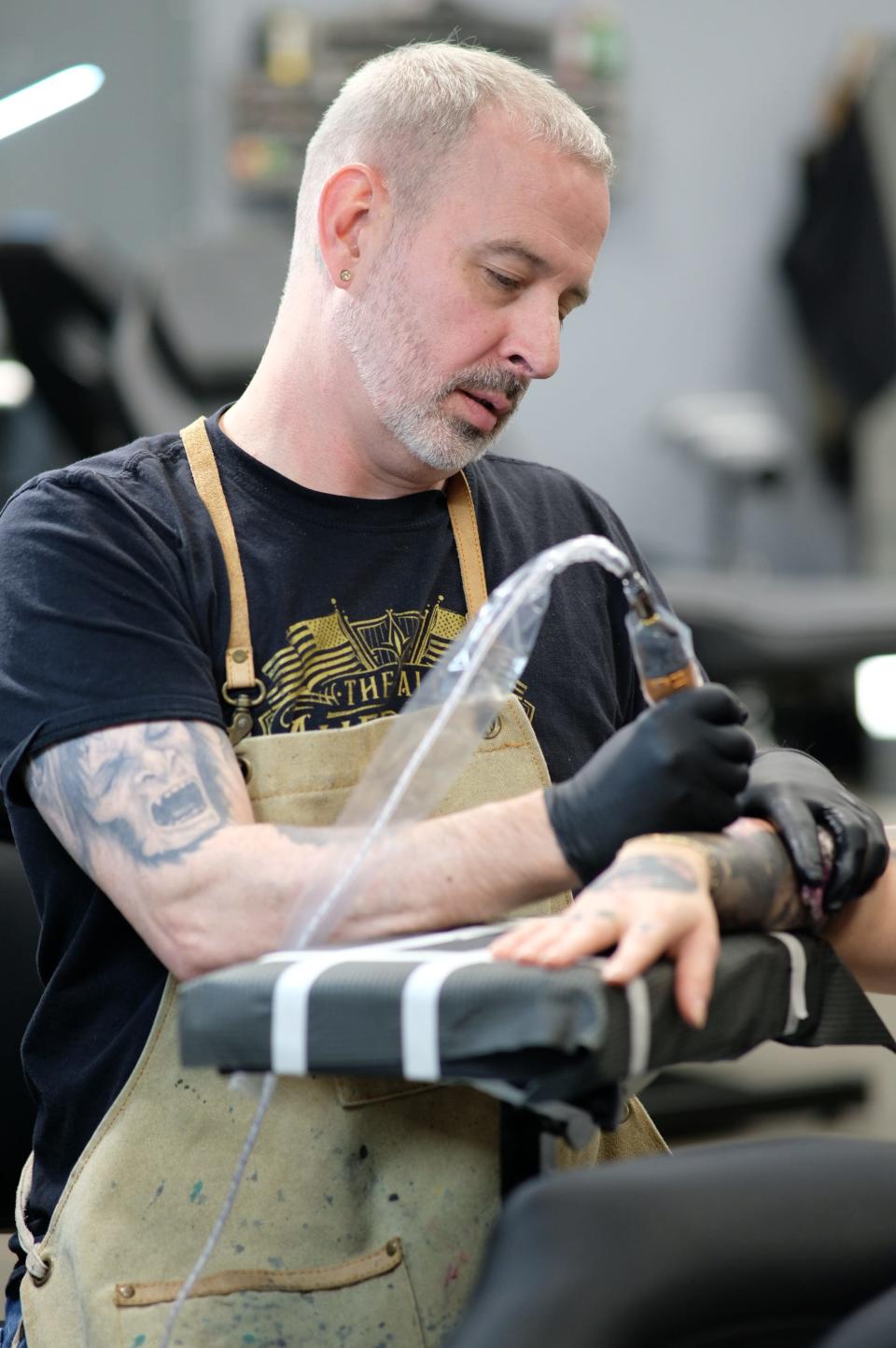 Sean McGarry, artist manager for All American Tattoo Society on Fort Liberty, provides a tattoo during a Dec. 19, 2023, grand opening on post.